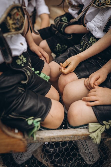 Kinder in traditioneller Lederhose sitzen zusammen