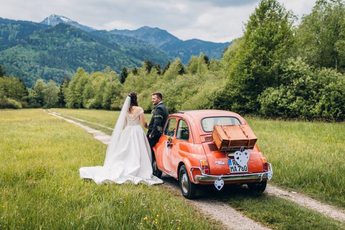 Hochzeitspaar mit altem rotem Auto